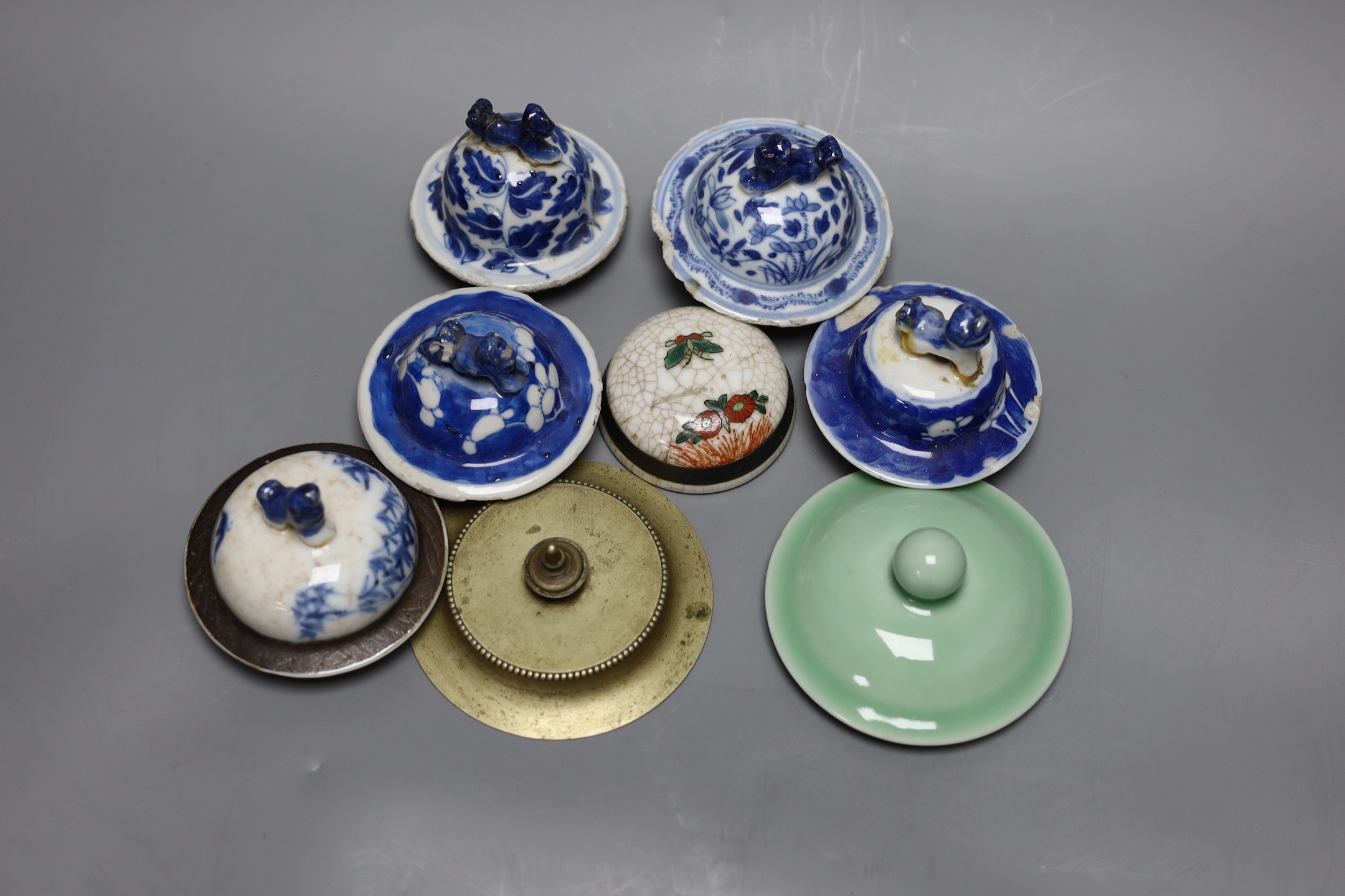 A collection of various Chinese porcelain lids/covers, a clobbered blue and white tea bowl, a brass hand warmer and a hardstone tablet